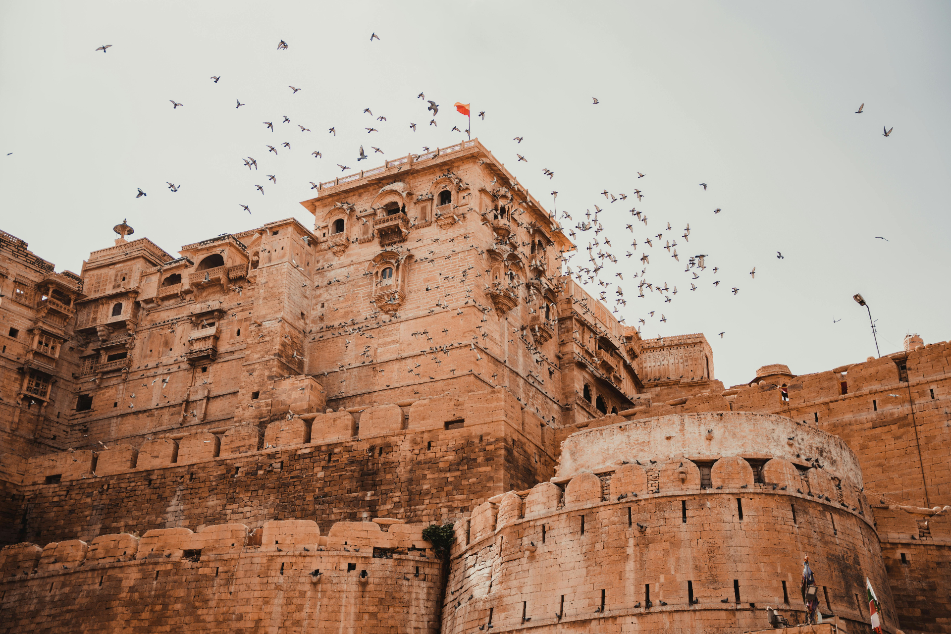 Jaisalmer Fort rising from the Thar Desert, a flock of birds circling its sandstone ramparts